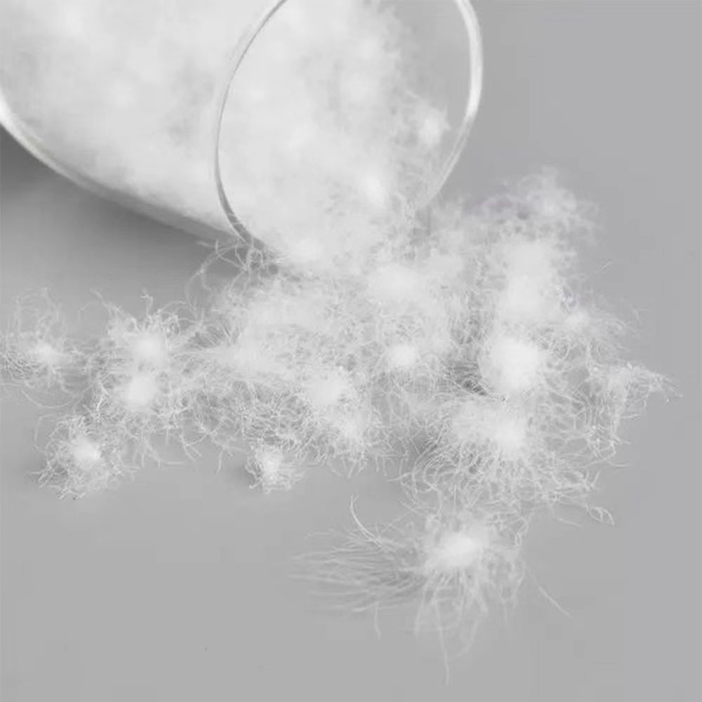 A single goose down feather on white linen